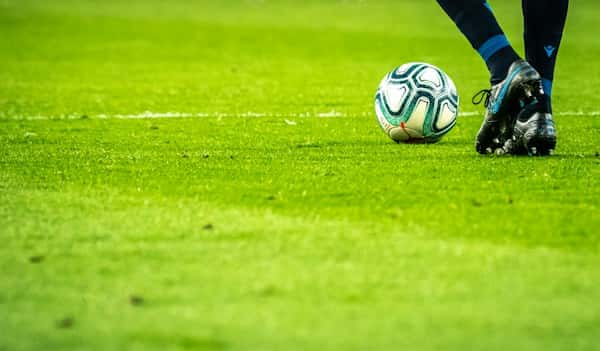 Ballon de football sur la pelouse au pied d’un joueur